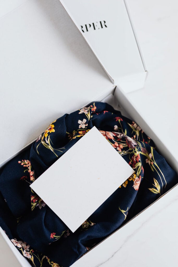 A post card on top of clothing in a branded shipping box