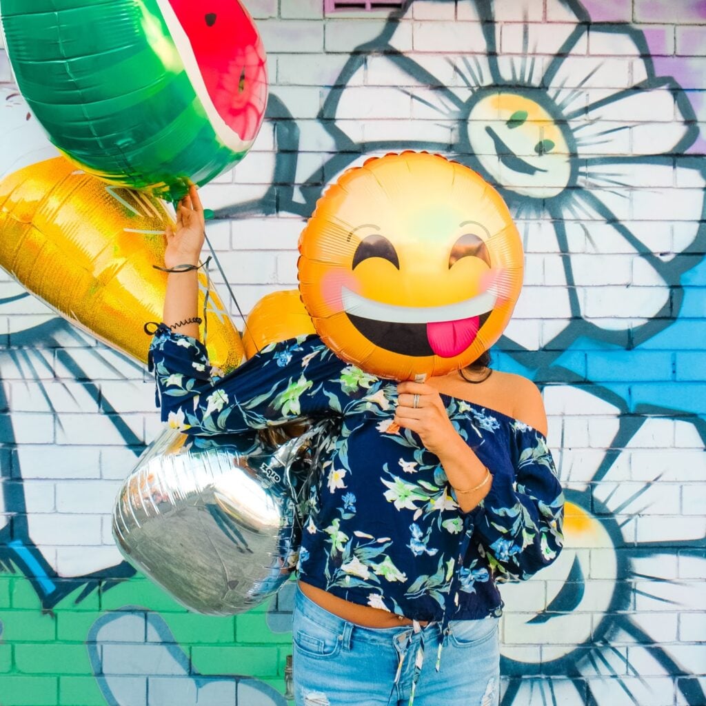 Woman with emoji balloon in front of their face