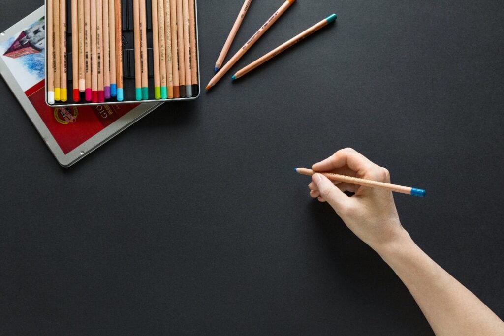 Designer hand holding colored pencil about to design draw