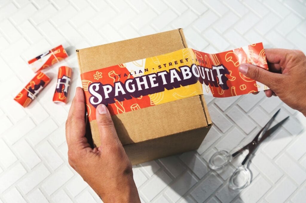 Custom branded tape being placed on a shipping box