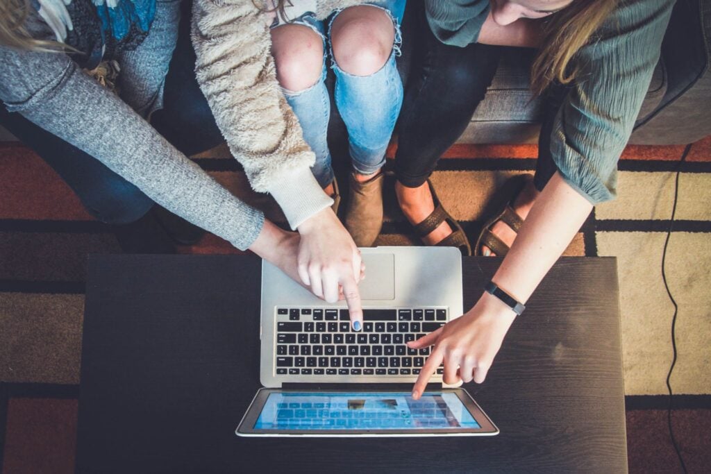 3 people pointing at a laptop