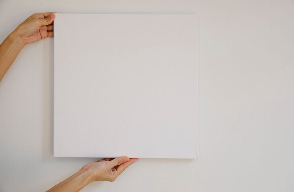 blank canvas being held against a white wall