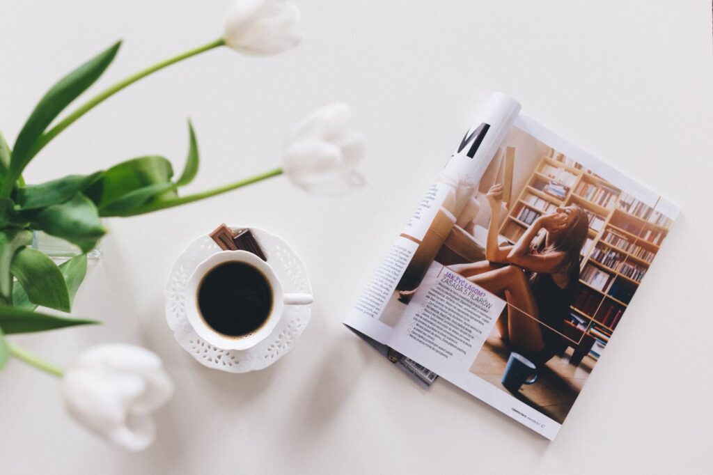 Magazine open on a table next to a cup of coffee