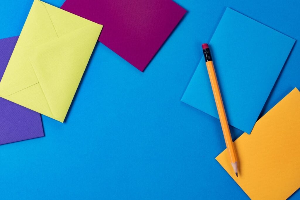 Multiple colorful envelopes on blue background with pencil