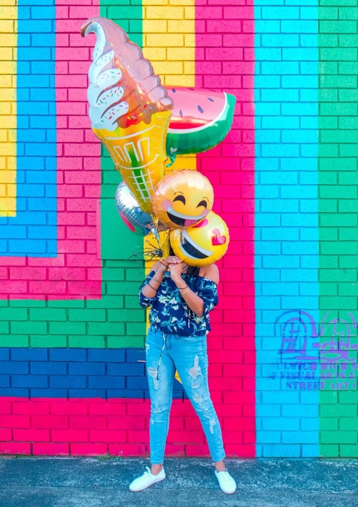 women holding big balloons in front of colorful wall
