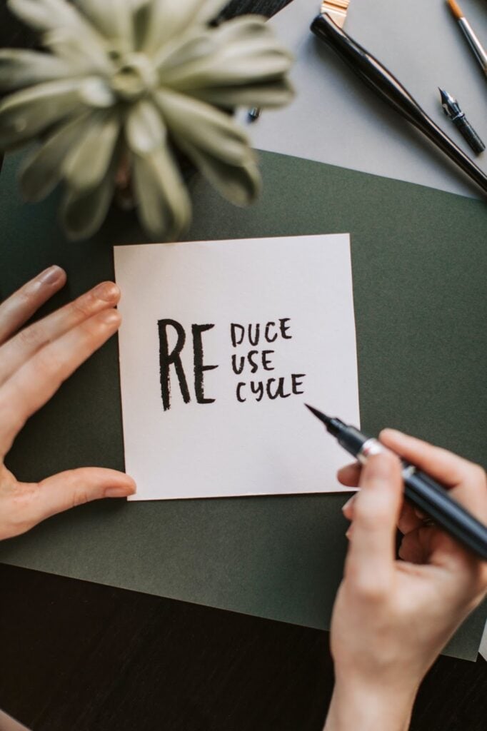 Reduce, reuse, recycle being written on a square piece of paper.