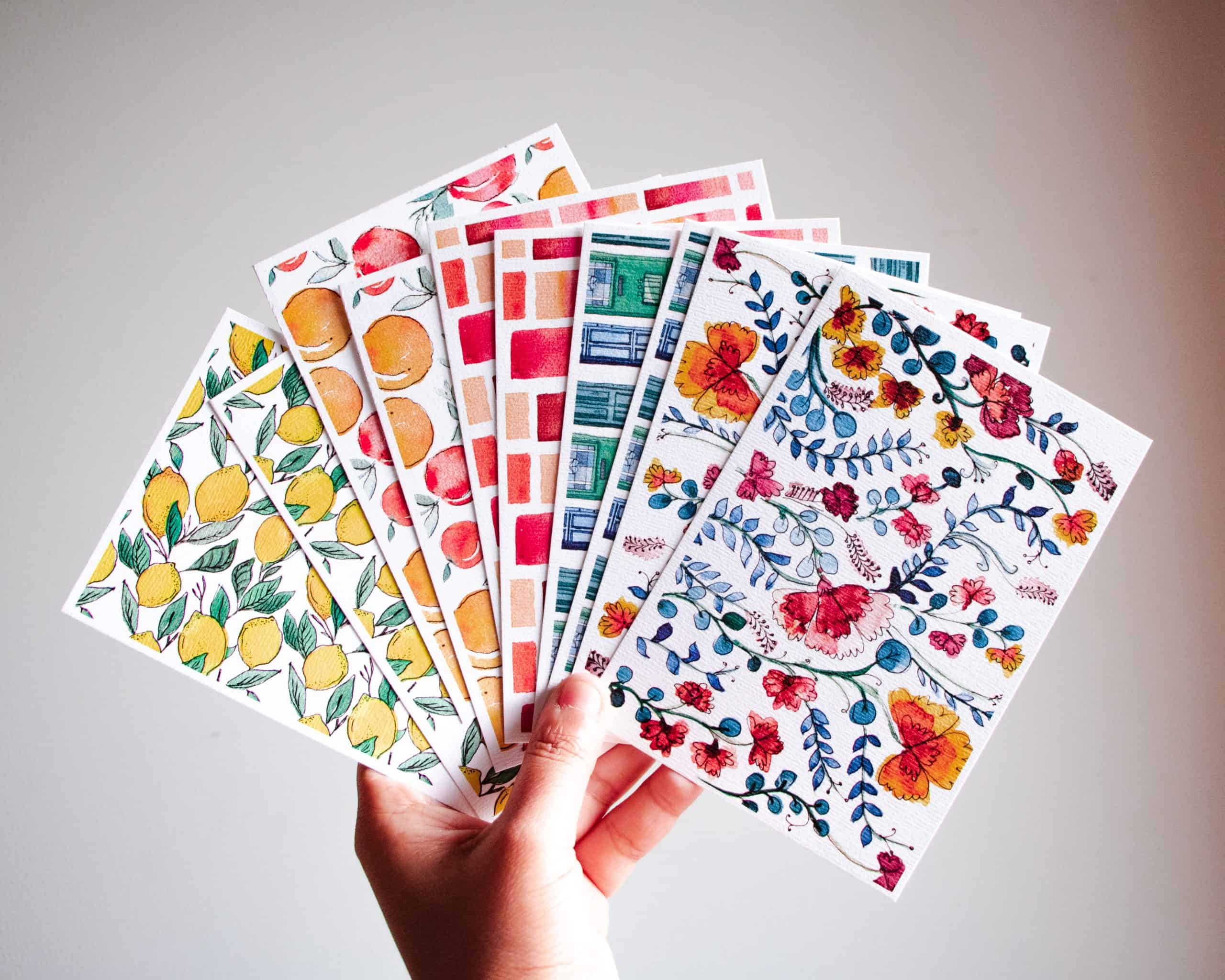Hand holding an array of colorful post cards